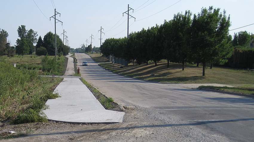 The sidewalk/trail curves to cross the road.