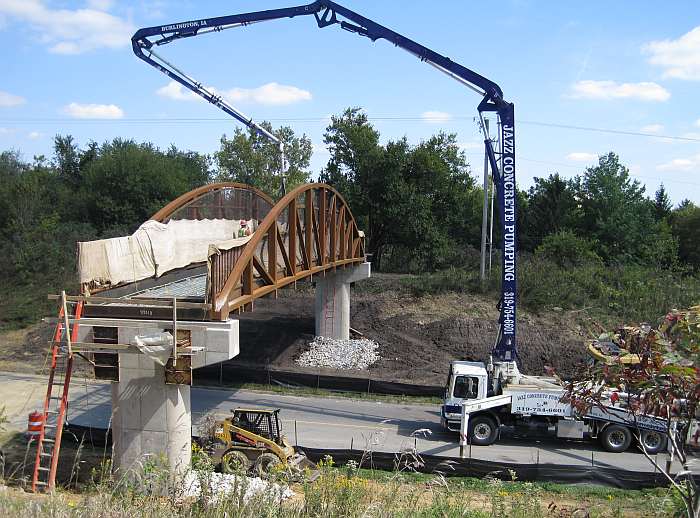 A front-end loader moves dirt below the bridge.