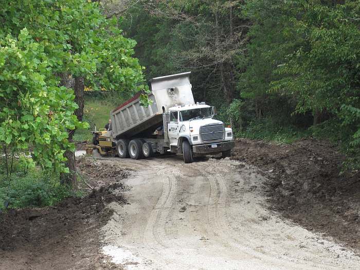 The dump truck fills the paver.