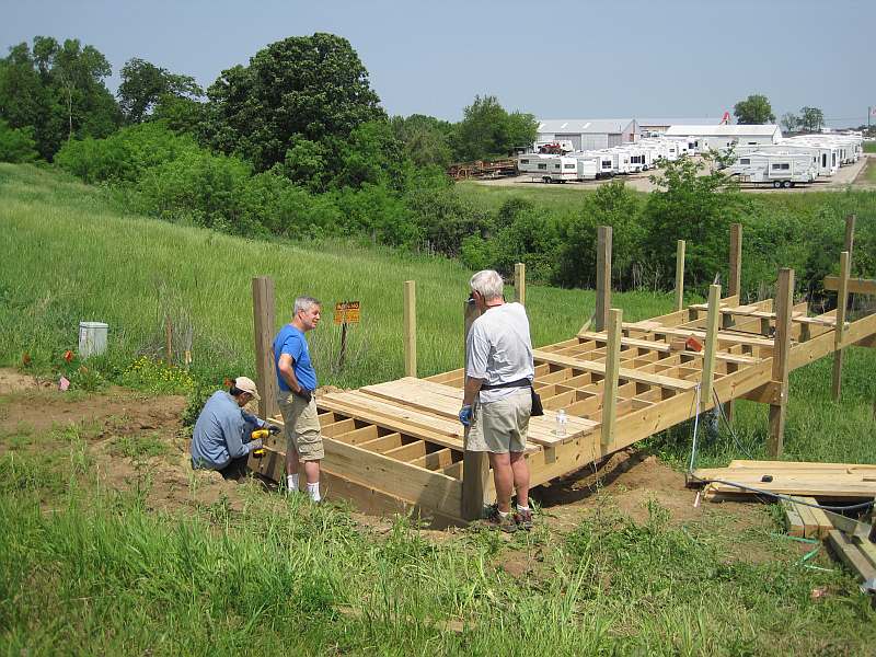 Stan Crowe and Dee Staufer (standing) discussing decking. Brian Stains putting in rim joist.
