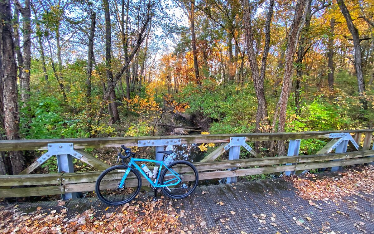 A bicycle resting on a wooden trail bridge in fall color