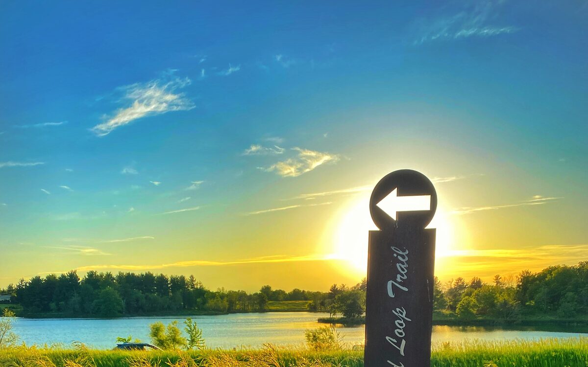 A Fairfield Loop Trail waymarker at sunset beside the water